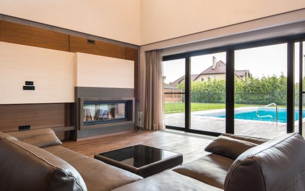 Spacious modern living room with glass doors opening to a poolside area.