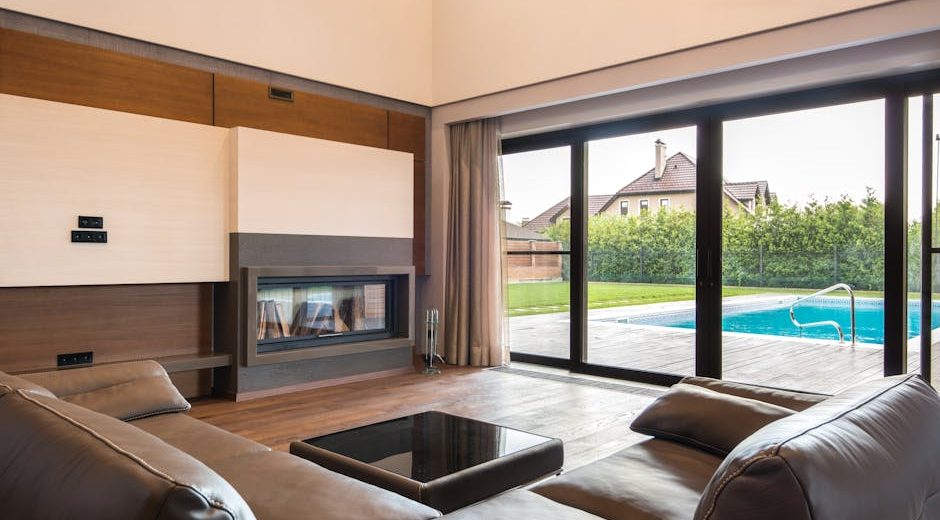 Spacious modern living room with glass doors opening to a poolside area.